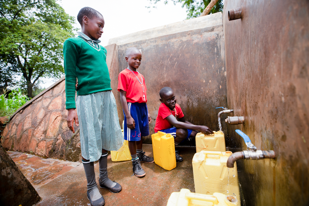 African students fill up their jerrycans at a well at their school