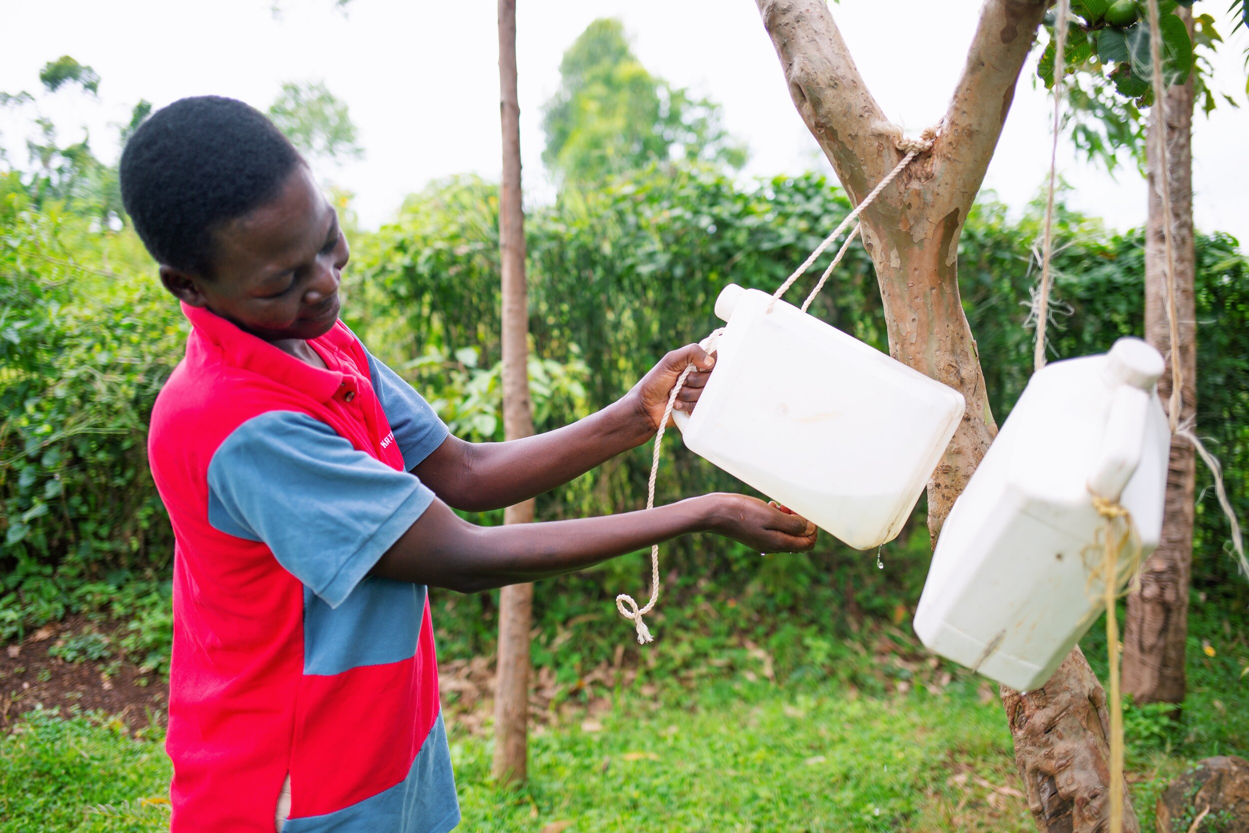 woman uses a tippy tap (a type of hand-washing station)