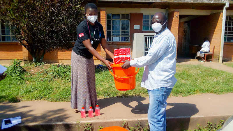 COPRED Staff, woman and man, at Bangwe Health center carrying supplies for the community hygiene facility