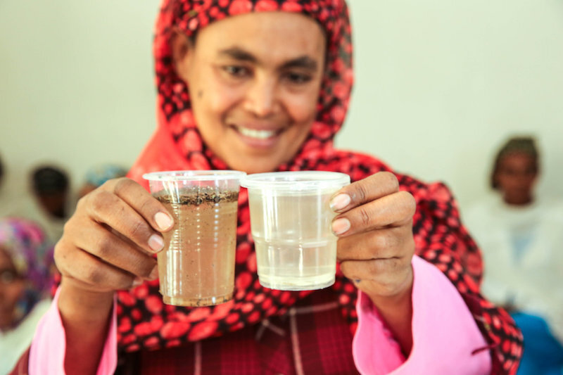 woman comparing dirty water to filtered water