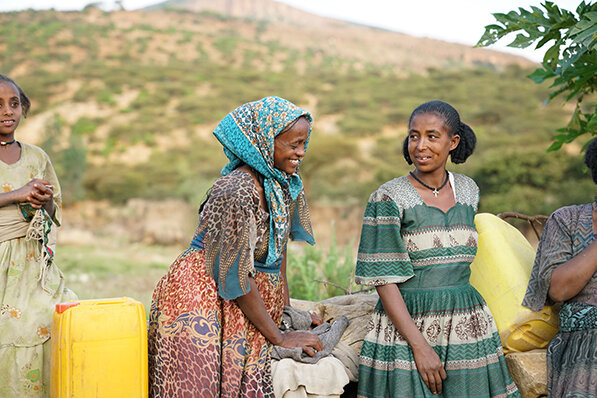 beneficiaries of blood:water’s clean water organization partner, drop of water, smile as they collect water