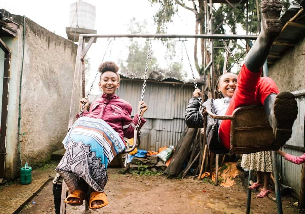 Two children swing on a swingset