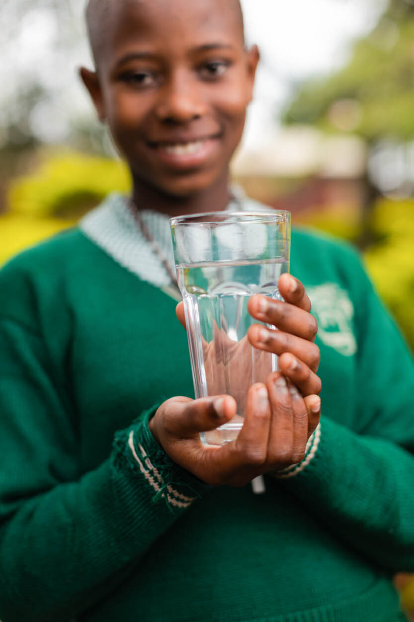 girl wearing school uniform holds a glass of clean water