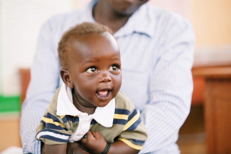 baby smiling baby in a striped shirt looks off to the side